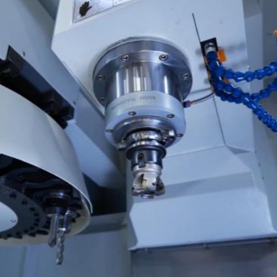 Tool changer carousel beside the spindle, with a milling tool fitted and a blue coolant hose